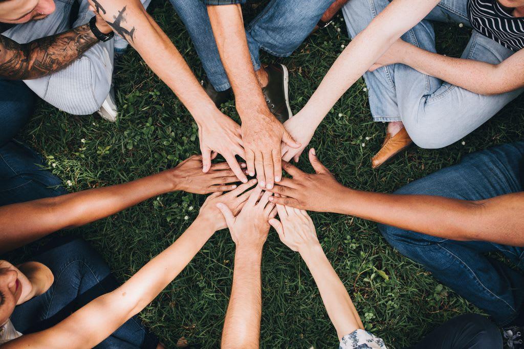 People stacking hands together in a park